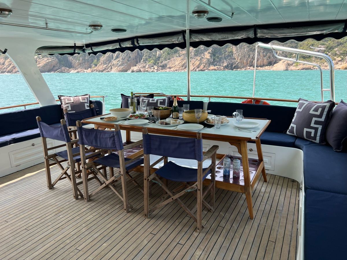 Covered aft deck set for lunch, turquoise bay behind