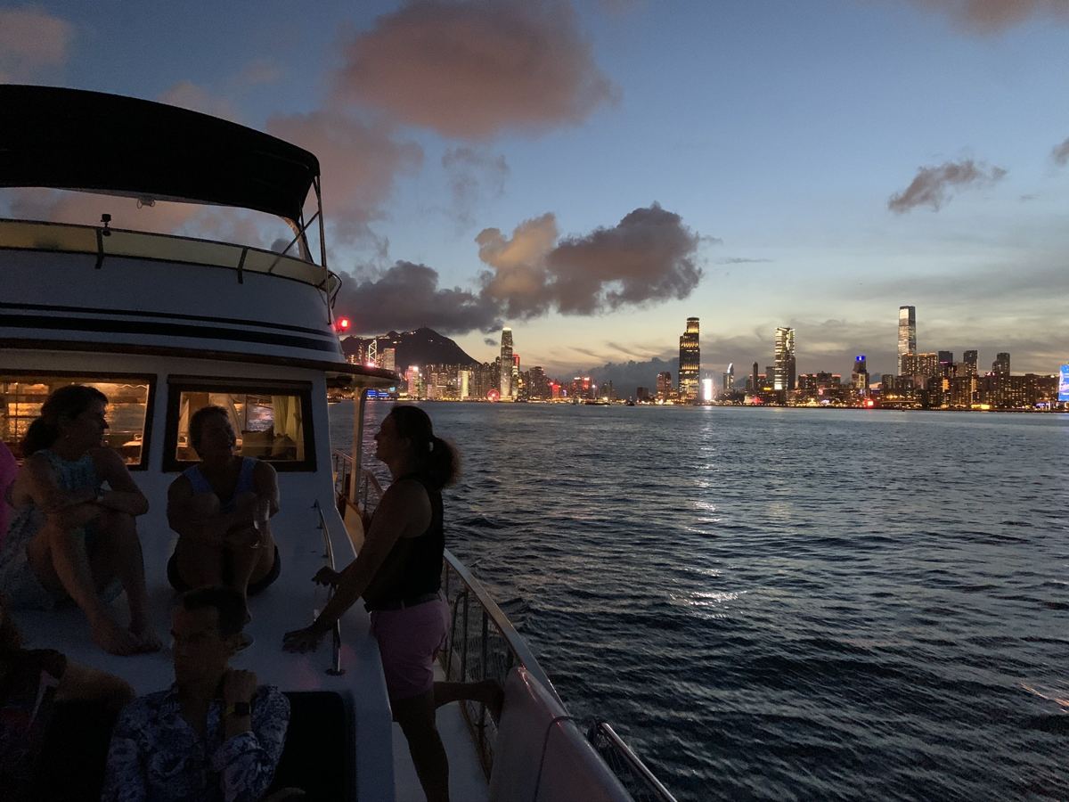 Guests on deck with the Hong Kong skyline at dusk